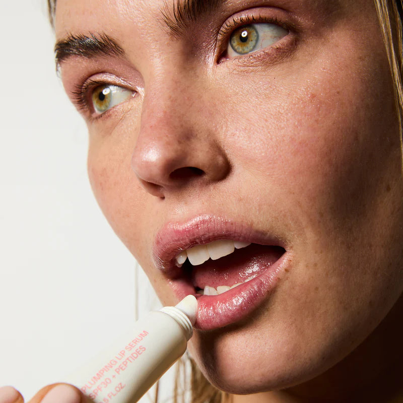 Femme appliquant Sérum lèvres glossy ultra shiny sur ses lèvres naturelles.